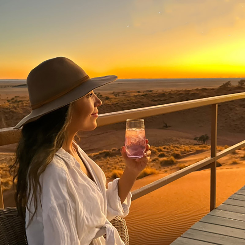 Lady enjoying a Gin & Tonic over a lodge sunset, Namibia